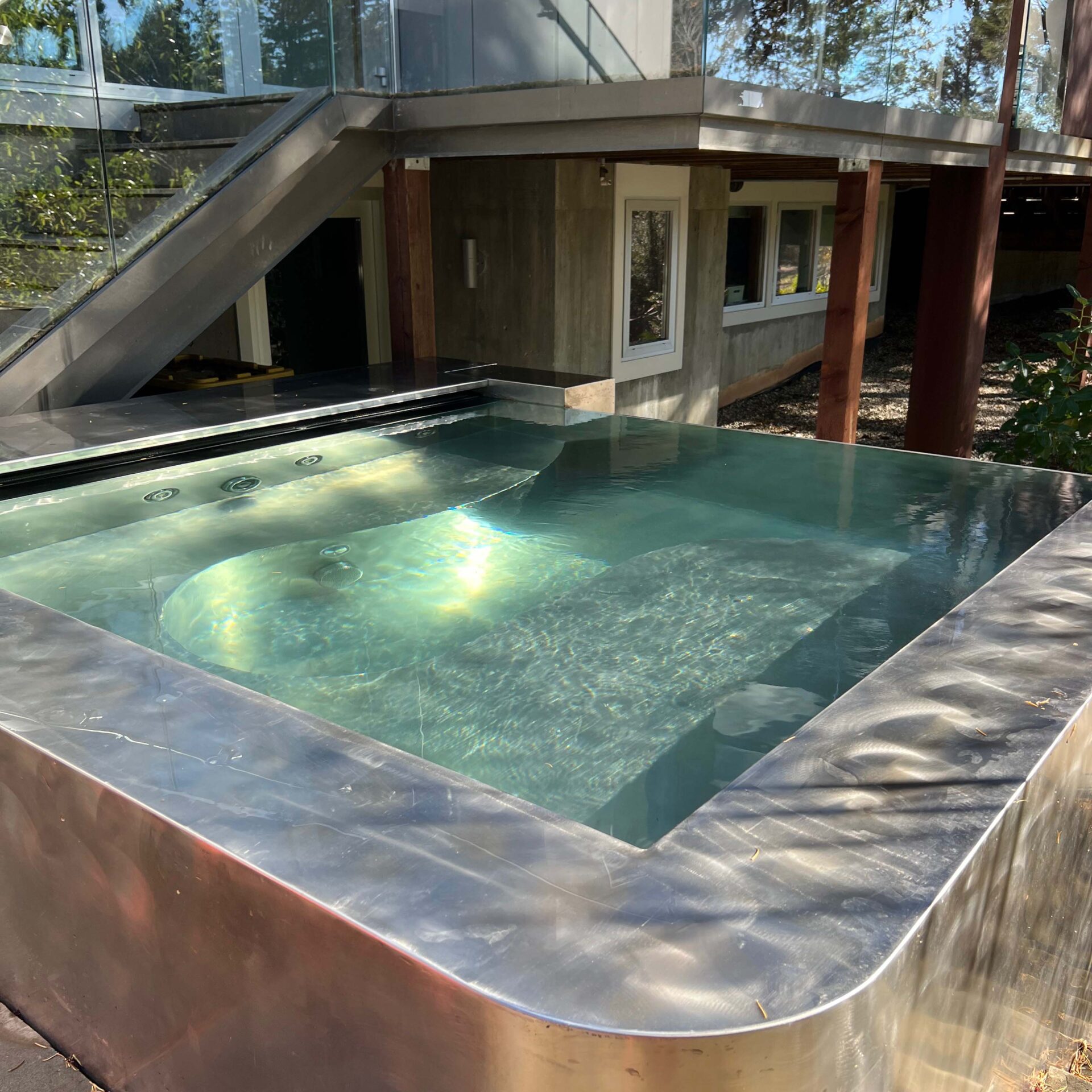 Modern building with large windows, featuring an elevated outdoor pool. Surrounded by trees, creating a serene and contemporary environment. No recognizable landmarks visible.