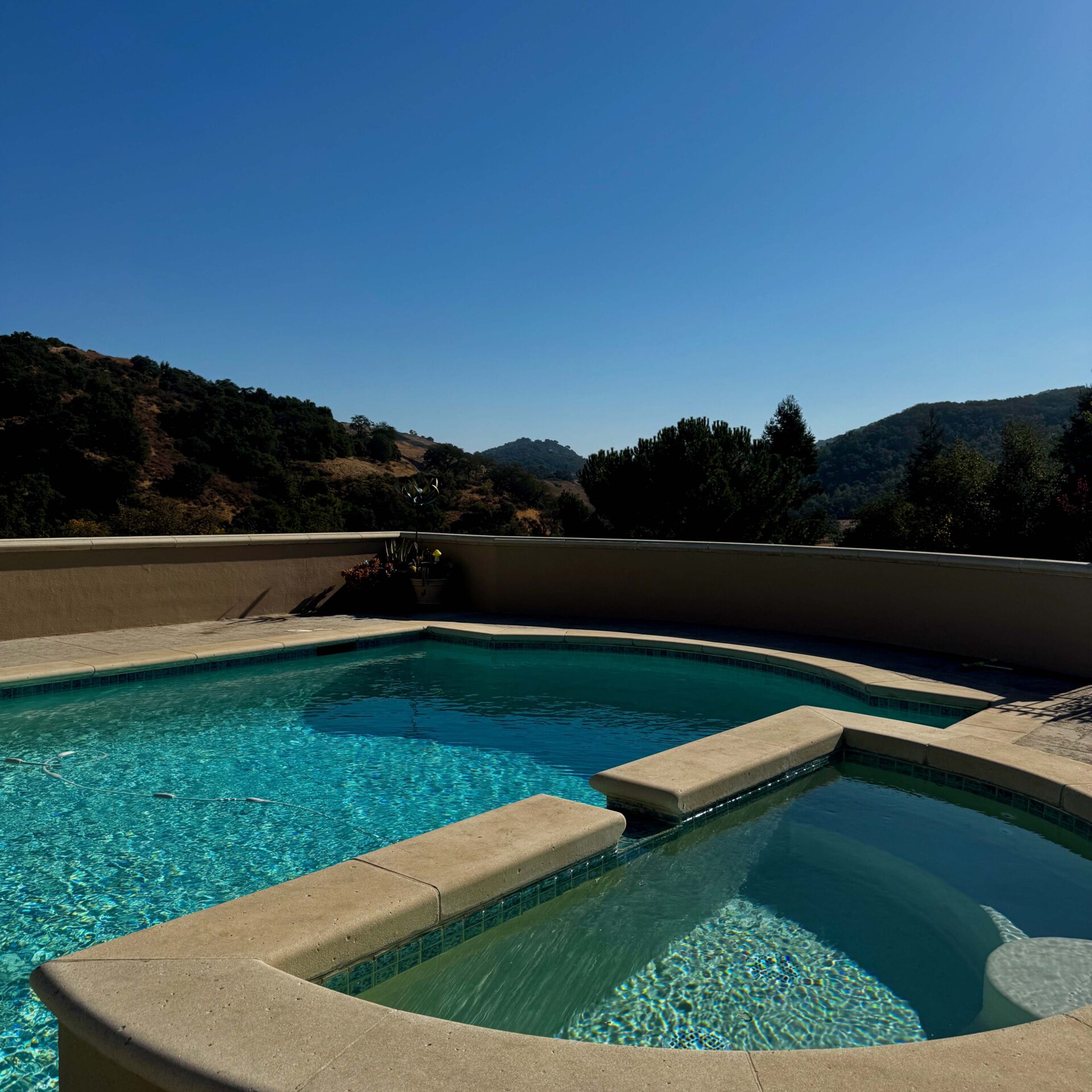 A serene pool overlooks scenic hills under a clear blue sky. No people or recognizable landmarks are visible in the image.