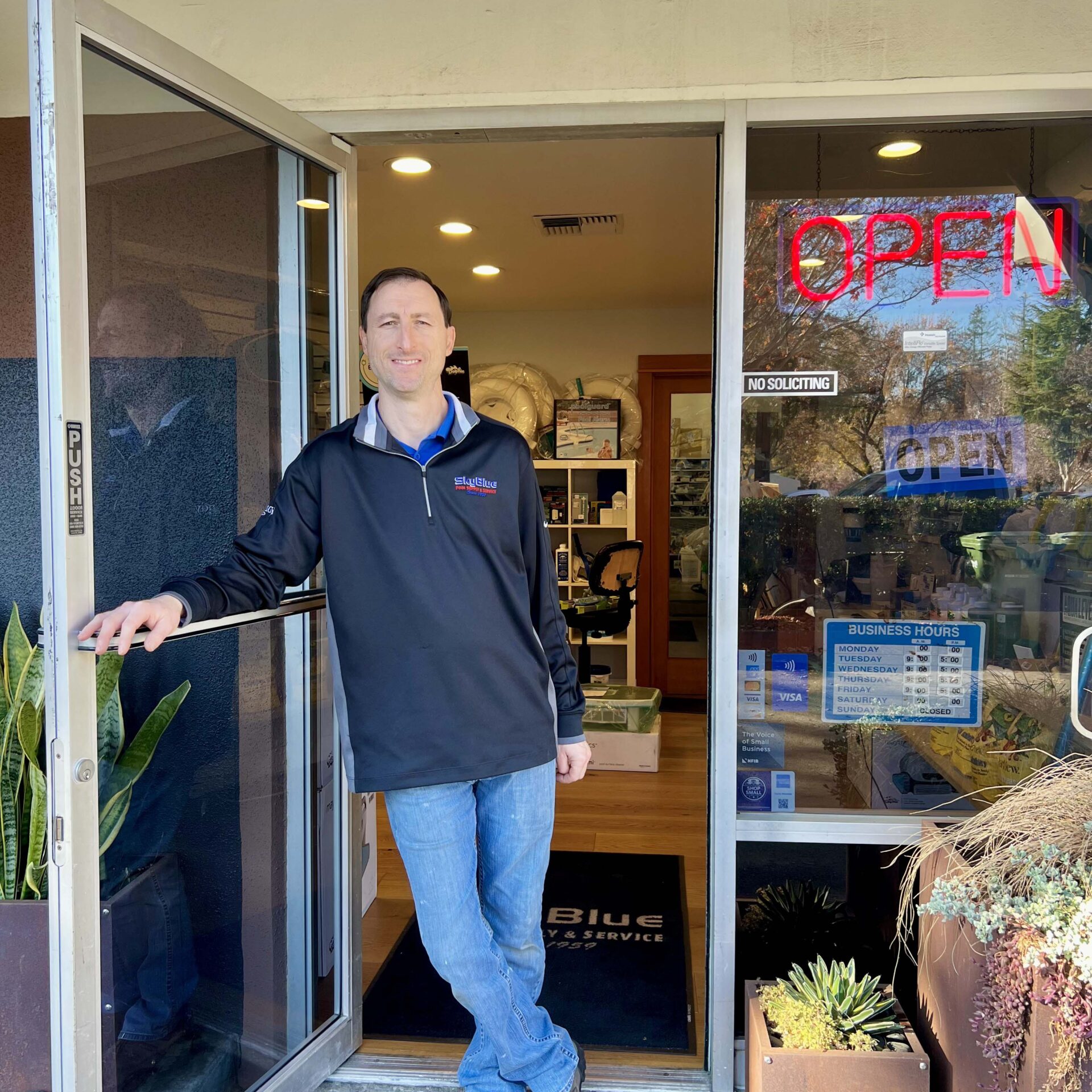 A person stands at the entrance of a business. An 