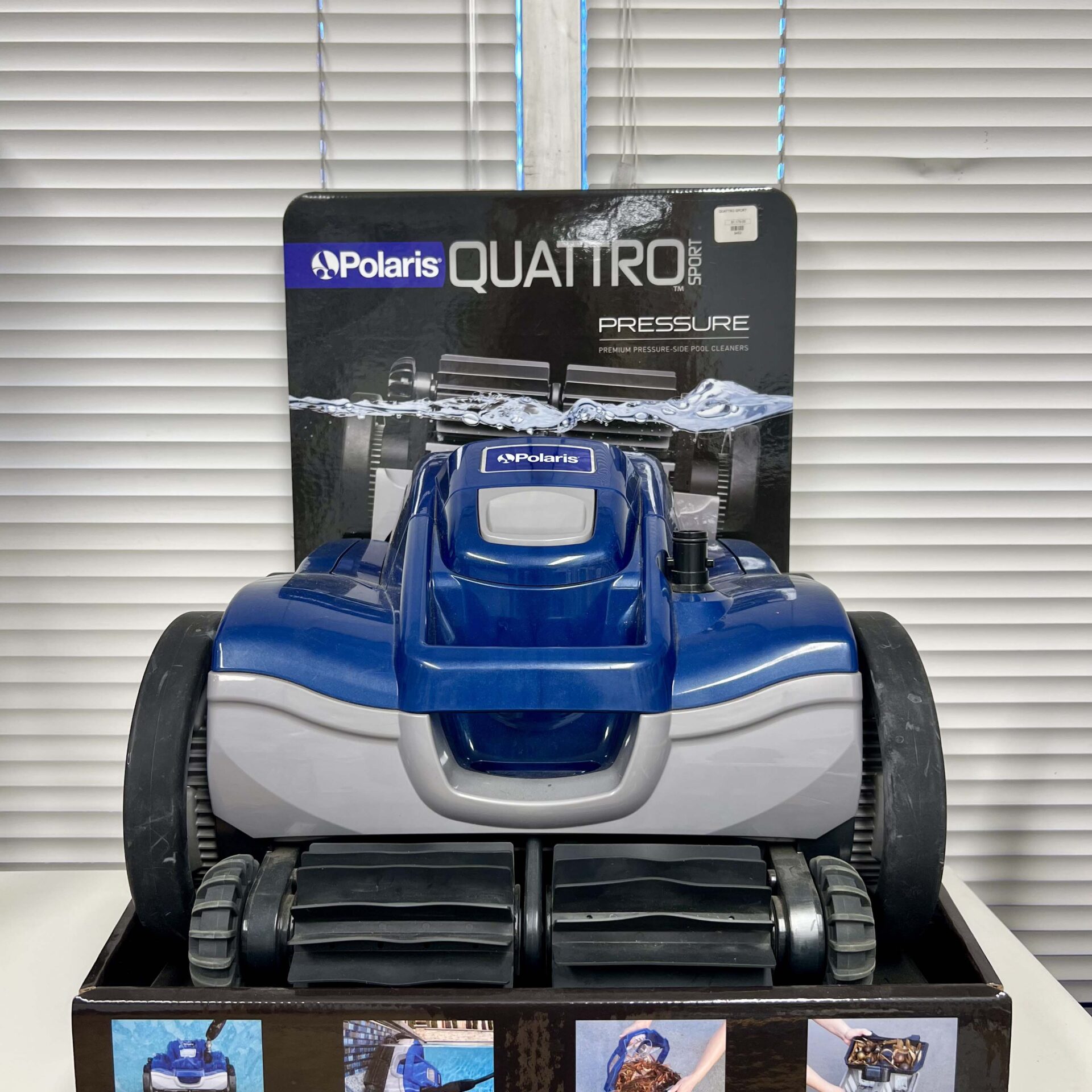 Blue and gray robotic pool cleaner displayed on a shelf, branded with 