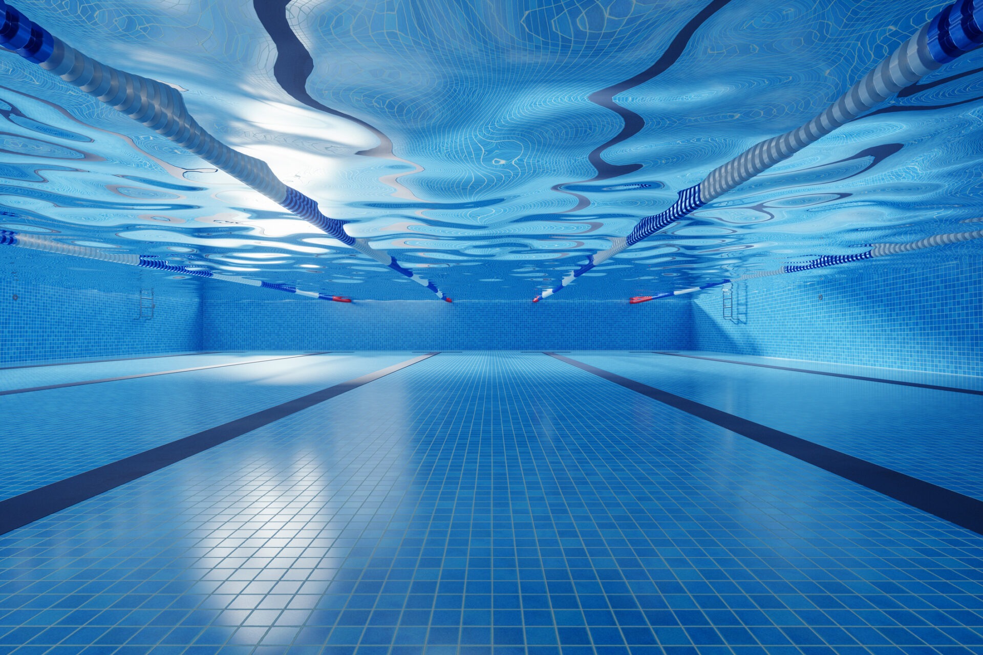 Underwater view of an empty swimming pool with blue tiles and lane dividers, creating a calm and serene atmosphere.