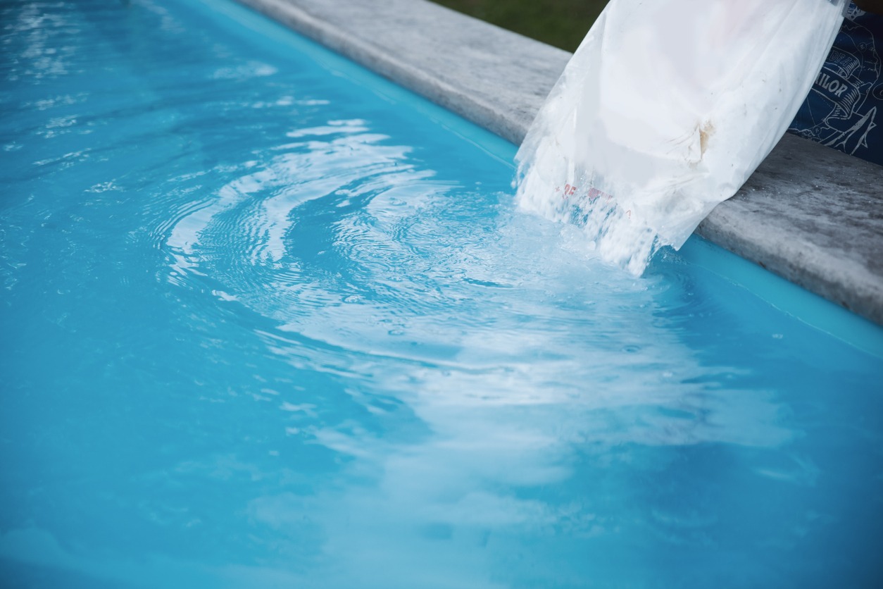 Someone helping to balance out their salt water pool with a bag of pool salt.